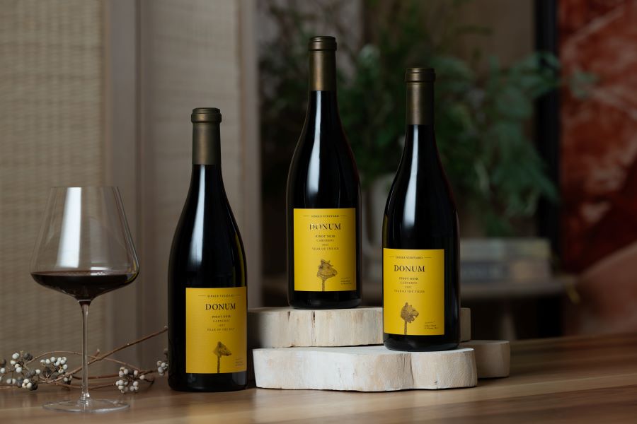 Three bottles of Donum Estate Wines with one glass of red wine