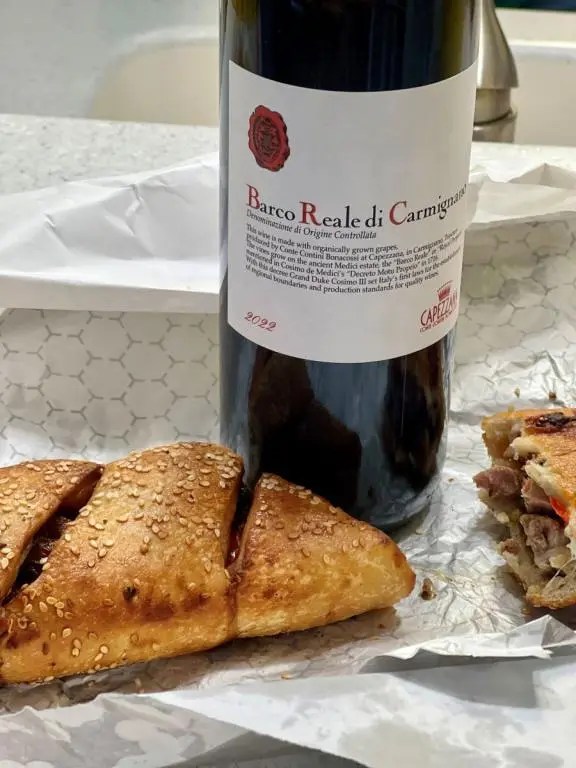 A bottle of 2022 Capezzana Barco Reale Di Carmignano DOC with a sausage roll